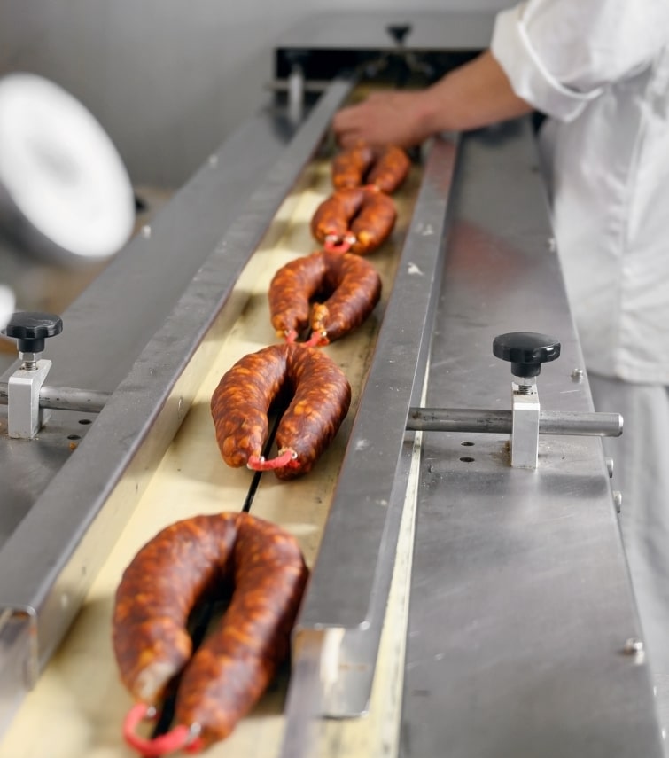 Wurst auf einem Förderband in einer Schweinefleischverarbeitungsanlage