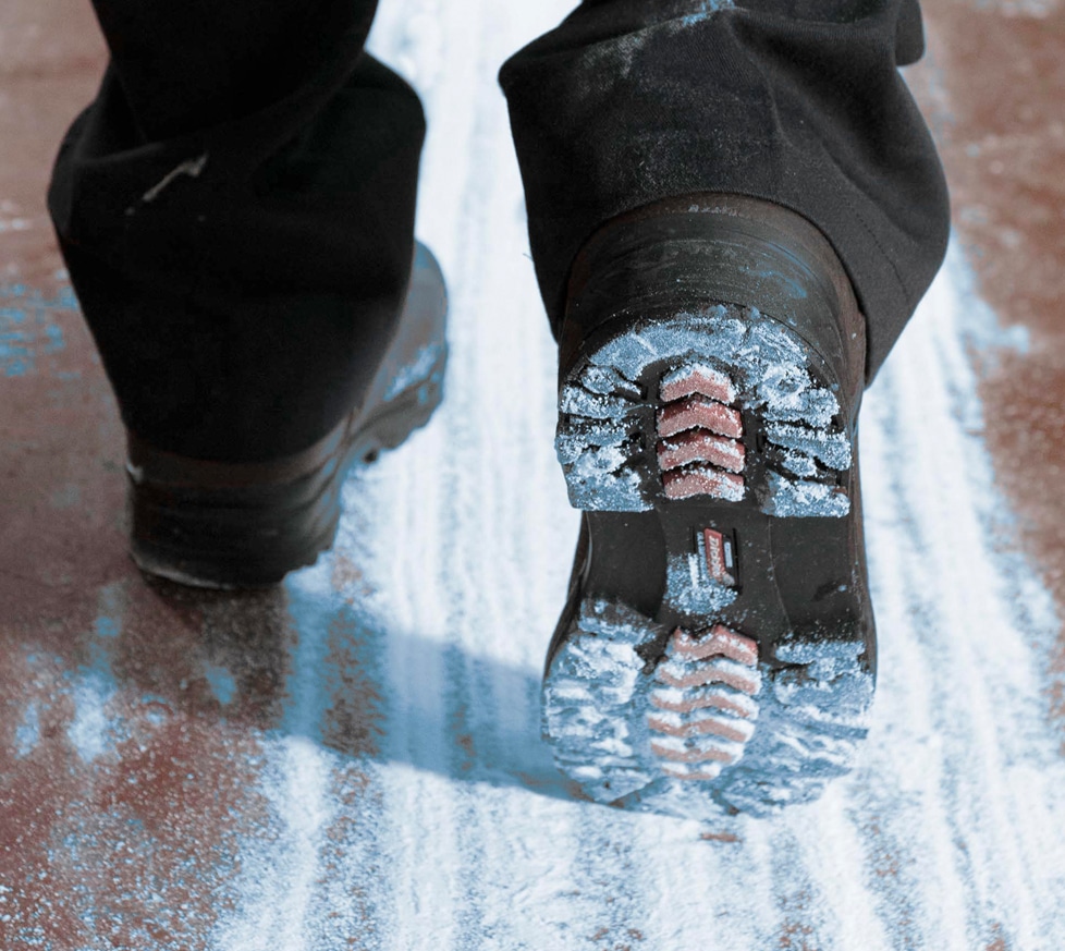 Sterilex Ultra Step in einer breiten Spur über den Boden und die Rückseite eines Stiefels verteilt, wobei das Pulver an der Sohle haften bleibt