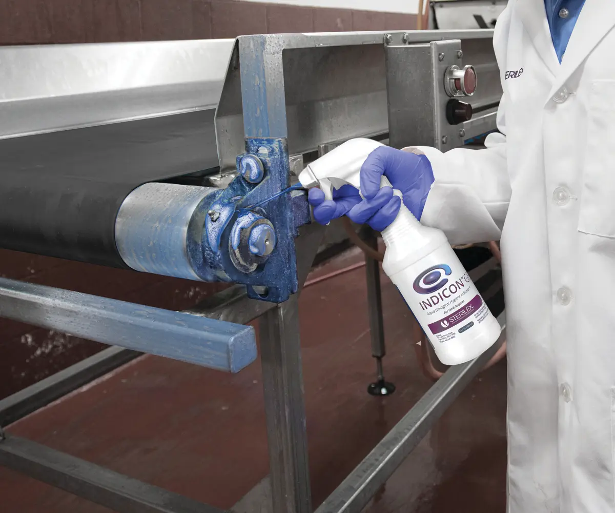 worker spraying Indicon Gel product onto conveyor