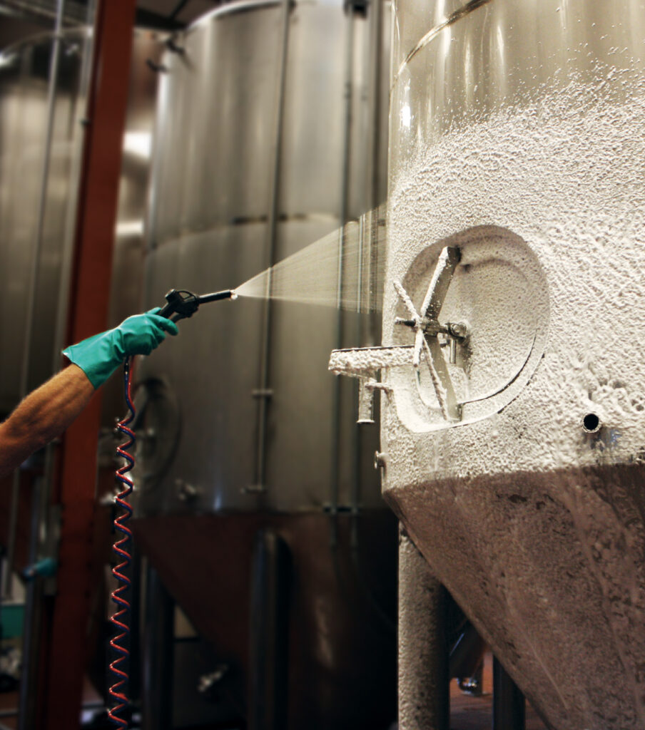 employee spraying foam product in beverage facility