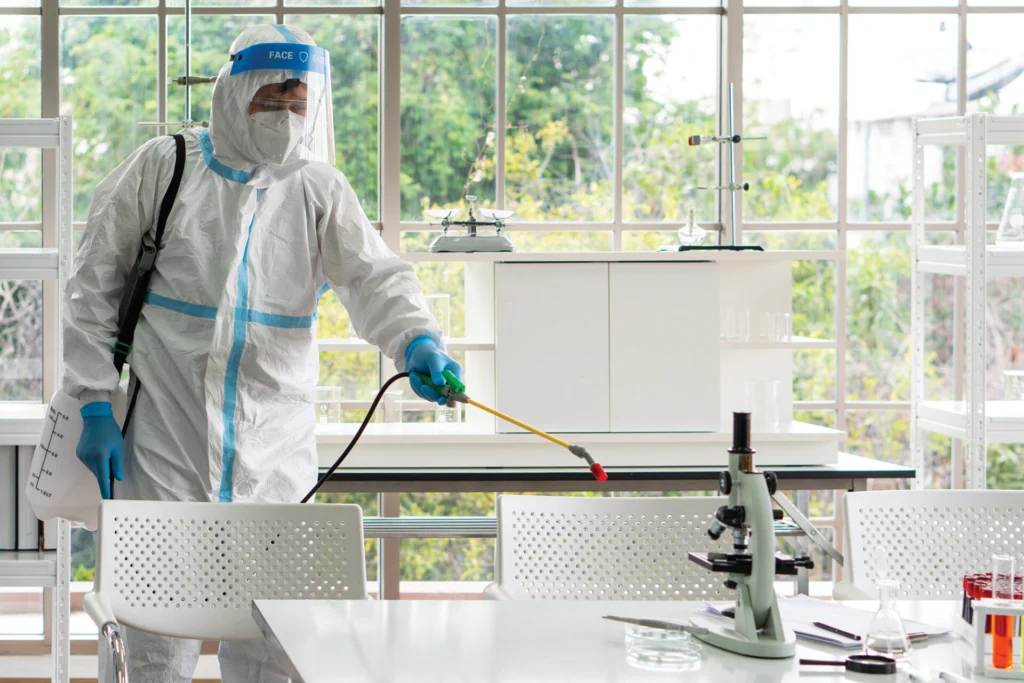 man in sterilized equipment spraying lab surfaces