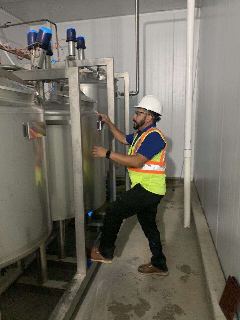 employee inspecting tanks in food facility