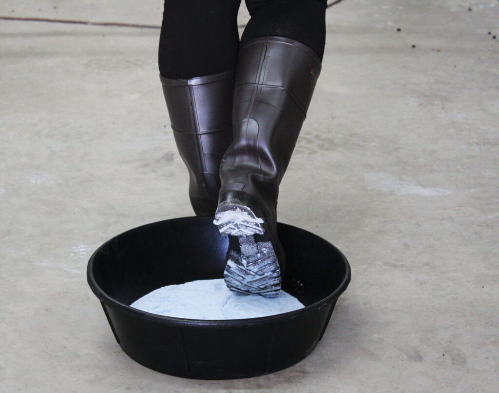 person with boots walking on three gal footpan with product